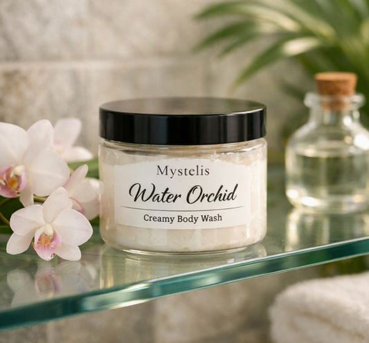 Mystelis Water Orchid Creamy Body Wash jar on a glass shelf in a tropical spa setting, surrounded by white orchids, greenery, and soft natural light.