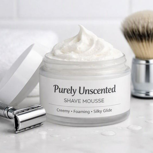 Open jar of Purely Unscented Shave Mousse on a white surface beside a silver razor and shaving brush — creamy whipped texture, handmade in Barrie Ontario.