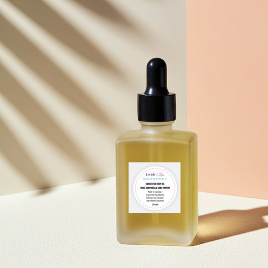 Square glass bottle of Unscented Body Oil with black dropper cap, labeled in English and French, displayed on a textured beige surface with warm natural shadows.